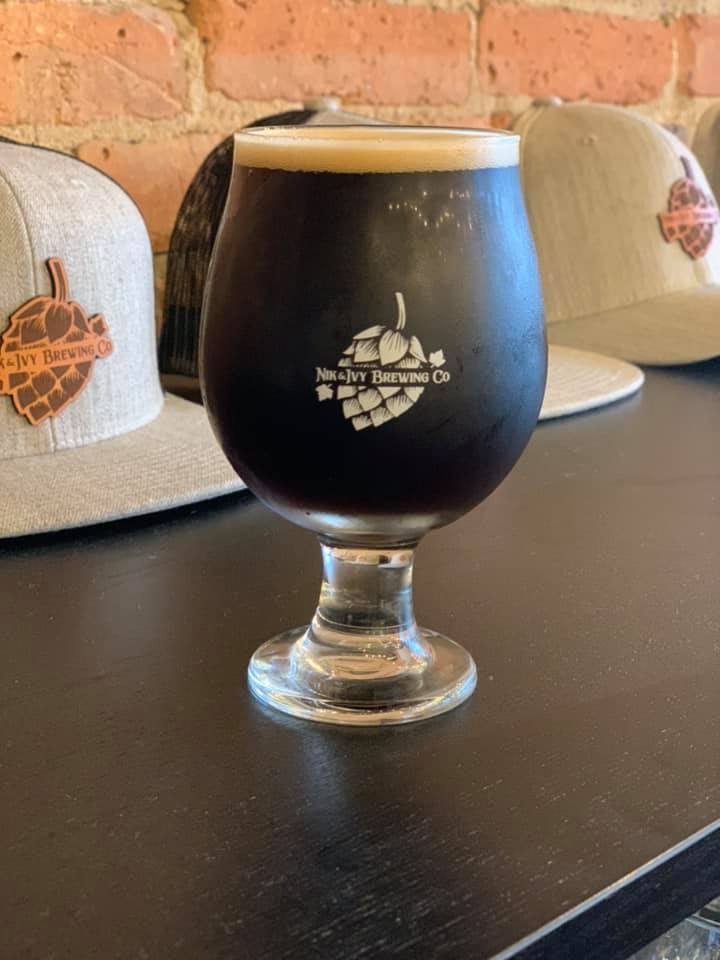 Glass of PBJ Porter fron Nik & Ivy, in front of Nik and Ivy hats