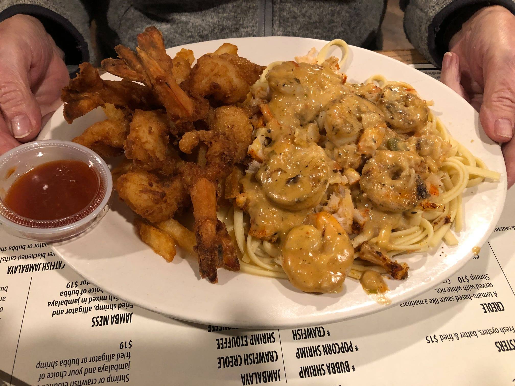 A plate of fried shrimp with with shrimp Alfredo on the side
